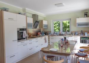 a kitchen with white cabinets and a wooden table at Firmen-Familien-Villa in Heiligengrabe