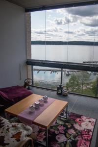 a living room with a table and a large window at Deluxe Apartment with Lake View and Sauna, Lahti in Lahti