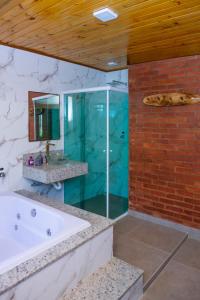 a bathroom with a bath tub and a glass shower at Chalés Cachoeira do Vale in Camanducaia