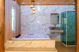 a bathroom with a tub and a glass shower at Chalés Cachoeira do Vale in Camanducaia +65 photos