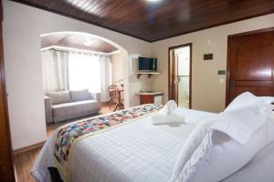 a bedroom with a large white bed and a couch at Hotel Pousada do Bosque in Canela