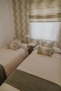 サンルーカル・デ・バラメダにあるApartamento El Mazacote Sanlúcar de Barramedaのベッドが2つと窓のある部屋