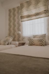 サンルーカル・デ・バラメダにあるApartamento El Mazacote Sanlúcar de Barramedaの白いベッドルーム(ベッド2台、窓付)