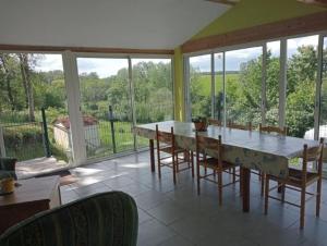 ein Esszimmer mit einem Tisch, Stühlen und Fenstern in der Unterkunft maison de campagne au calme, Le Lude in Le Lude