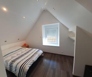a attic bedroom with a bed and a window at La Grange in Bretteville