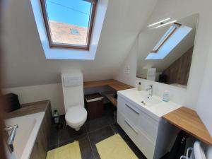 ein Badezimmer mit einem WC, einem Waschbecken und einem Dachfenster in der Unterkunft La Grange in Bretteville
