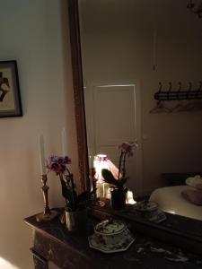 Cette chambre comprend une table avec des fleurs et un miroir. dans l'établissement Castel La Bergerie, à Laglorieuse