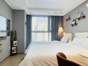 Un dormitorio con una gran cama blanca y una mesa en INN-The City MyeongDong en Seúl