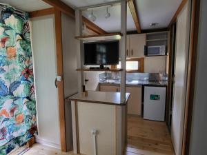 Una pequeña cocina con televisión en una casa diminuta. en Camping El Picachuelo, en El Berrueco