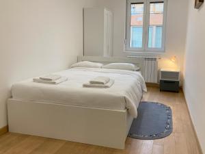 uma cama branca num quarto branco com uma janela em The Door em Trieste