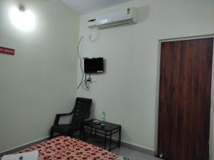 a room with a bed and a chair and a television at Lucy Guest House in Bogmalo