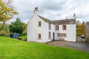 een wit huis op een heuvel met een groene tuin bij Townend Farmhouse - Ullswater in Watermillock