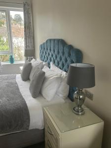a bed with a blue headboard and a table with a lamp at The Millbrook B&B in Torquay