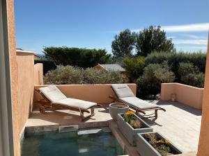 eine Terrasse mit 2 Stühlen und einem Pool mit Wasser in der Unterkunft La jasse in Cabrières-dʼAigues
