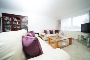 uma sala de estar com um sofá branco e almofadas roxas em GuestReady - Spacious 2BR Flat in Peaceful Hove em Brighton & Hove
