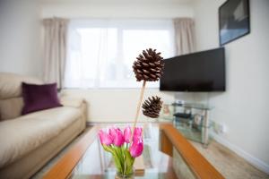 a vase with a pine cone and pink flowers on a table at GuestReady - Spacious 2BR Flat in Peaceful Hove in Brighton & Hove