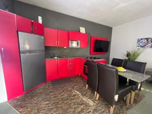 a kitchen with red cabinets and a table with black chairs at Luxurious two bathroom apartment Paramaribo, Zorg en Hoop in Paramaribo