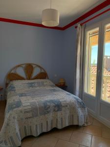 a bedroom with a bed and a large window at Gite LA FONTAINE Famille Amis Relais Motards in Peyriac-de-Mer