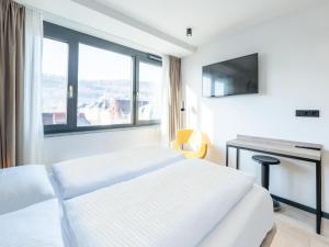 a bedroom with two beds and a desk with a television at B&B HOTEL Albstadt-Hbf in Albstadt
