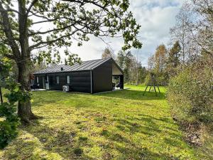 Ein schwarzes Haus in einem Garten mit einem Baum in der Unterkunft 8 person holiday home in L s in Læsø