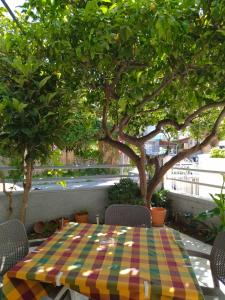 a table with a checkered table cloth sitting under a tree at COSY Living Apartment 1 in Kos Town