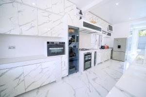 a white kitchen with white marble floors and appliances at El Amo Lakeview villa in Entebbe