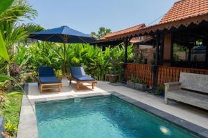 una piscina con dos sillas y una sombrilla en Villa Lalupa Joglo, en Canggu