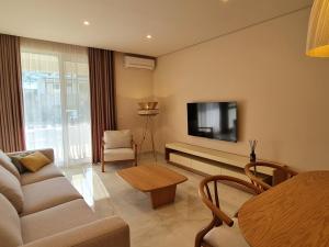 - un salon avec un canapé et une télévision dans l'établissement Gjiri i Lalzit - San Pietro - Savita Premium Apartments, à Durrës