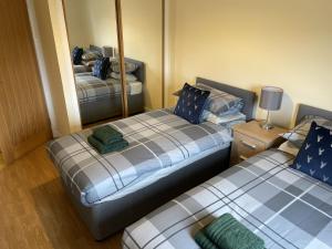 Dos camas en una habitación con espejo. en TAIGH CATHIE, 67 Alma Road, en Fort William