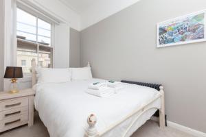 um quarto com uma cama branca e uma janela em GuestReady - Espaço maravilhoso em Brighton e Hove em Brighton & Hove