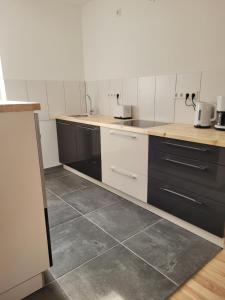 a kitchen with white and black cabinets and tile floors at Haus Sonnen mit 3 Apartments in Nettetal