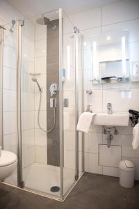 ein Bad mit einer Dusche und einem Waschbecken in der Unterkunft Hotel Regina in Würzburg