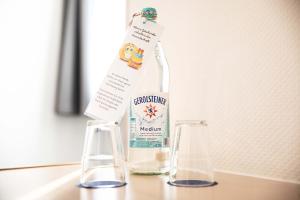 a bottle of alcohol sitting on a counter with two glasses at Hotel Regina in Würzburg