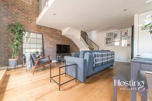 a living room with a blue couch and a brick wall at The Henley Retreat in Henley on Thames