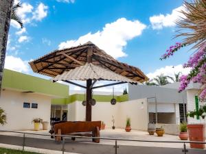 un patio con sombrilla frente a una casa en Hotel Sol Nascente en Arapiraca