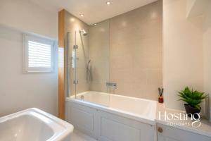 een witte badkamer met een bad en een douche bij Spacious Luxury Cottage With Roof Terrace Close To The River Thames in Henley on Thames