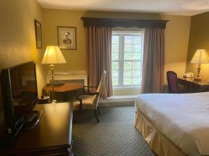 a hotel room with a bed and a desk and a window at Brandywine River Hotel in Chadds Ford
