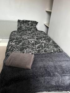 Lovely 2-Bed House in Liverpool في ليفربول: غرفة نوم بسرير وبطانية بيضاء وسوداء