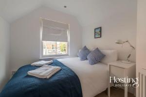 a bedroom with a bed with a blue blanket and a window at Stunning Character House In The Centre of Henley in Henley on Thames