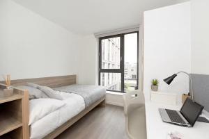 a white bedroom with a bed and a desk with a laptop at Modern and Bright Ensuite at St Mungo's in Glasgow for Students Only in Glasgow