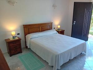 a bedroom with a white bed and two night stands at Bandi House in San Teodoro