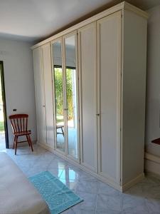 a bedroom with white wardrobes and a chair at Bandi House in San Teodoro