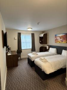 a hotel room with two beds and a desk at Highland Gate, Stirling by Marston's Inns in Stirling