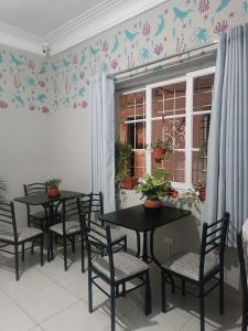 Quinoa Backpackers Hostel في ليما: طاولتين وكراسي في غرفة بها فراشات على الحائط