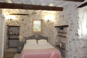 a bedroom with a bed in a stone wall at Le Pigeonnier, gîte des Lucioles en Provence in Montségur-sur-Lauzon