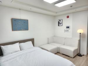 束草市的住宿－Sokcho Summitbay 1402 "Ocean View"，白色卧室配有床和沙发
