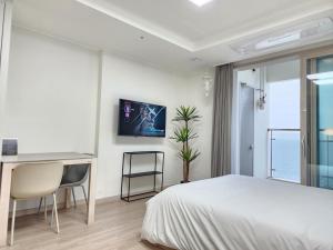 a bedroom with a bed and a desk and a monitor at Sokcho Summitbay 1402 "Ocean View" in Sokcho