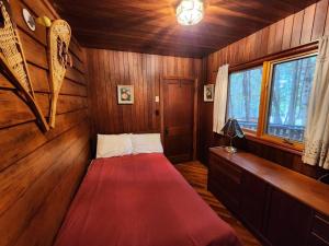 1 dormitorio con 1 cama roja en una habitación de madera en Private Rustic Lodge w/ Lakefront Views, en Minden