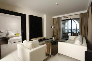 a bedroom with a bed and a living room with white furniture at Dar El Marsa Hotel & Spa in La Marsa