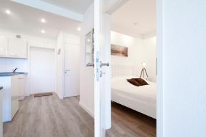 a white bedroom with a bed and a kitchen at Panoramic App A14-zehn in Sierksdorf +19 photos